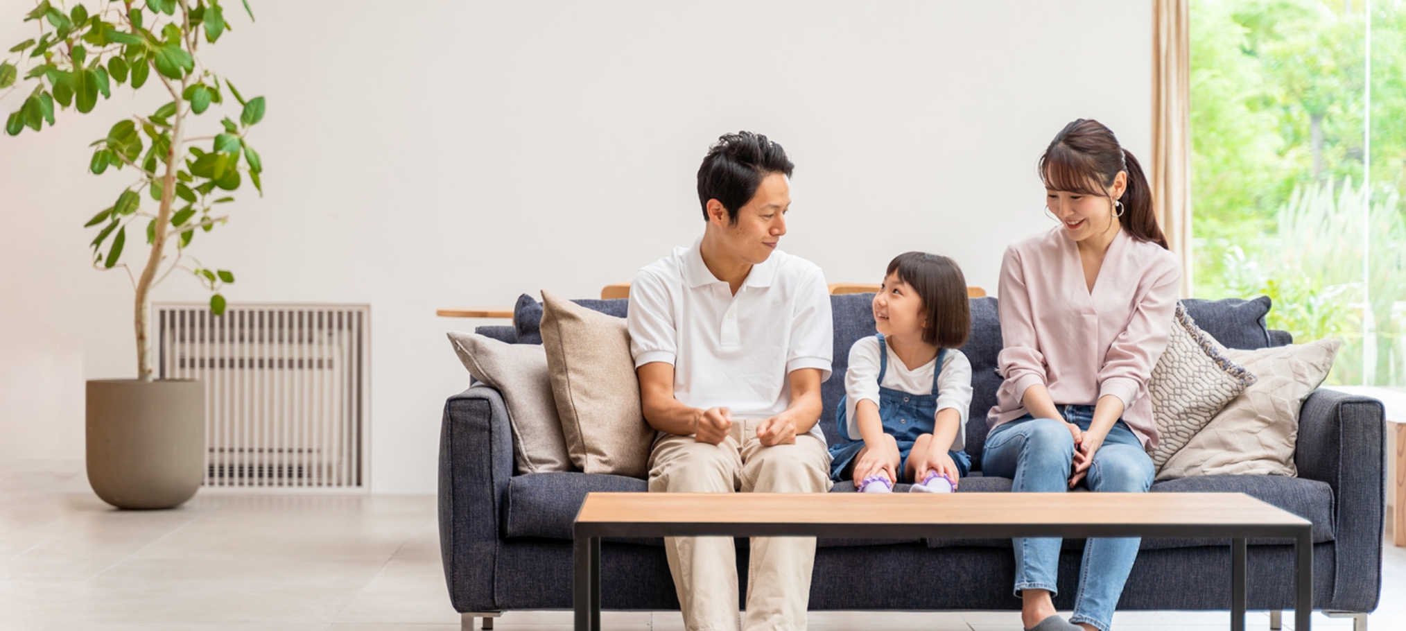 広いリビングで小学生のこどもとリラックスして過ごす夫婦